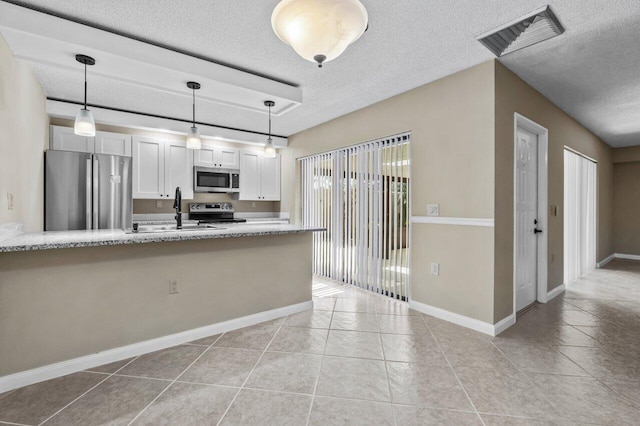 kitchen with pendant lighting, white cabinetry, sink, stainless steel appliances, and a textured ceiling