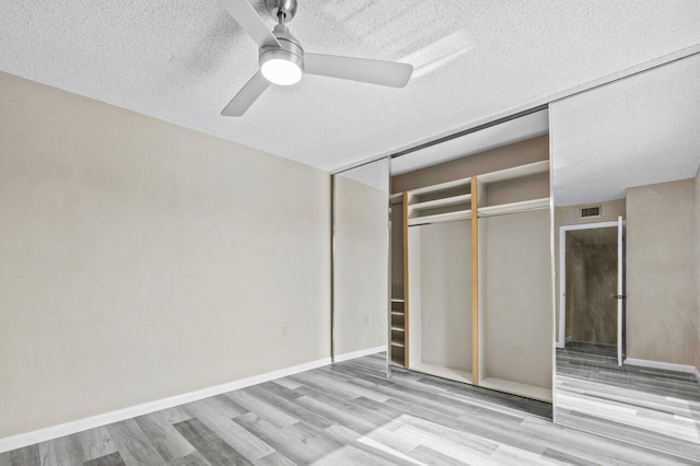 unfurnished bedroom with ceiling fan, a closet, a textured ceiling, and light hardwood / wood-style flooring