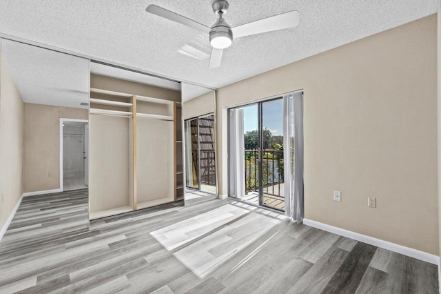 unfurnished bedroom featuring ceiling fan, access to outside, a textured ceiling, and light wood-type flooring