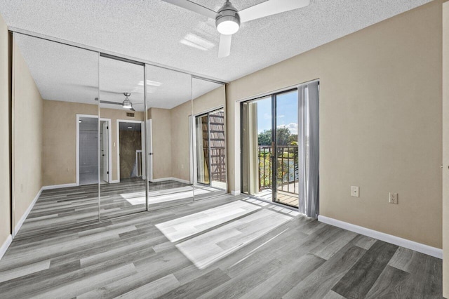 empty room with ceiling fan, wood-type flooring, and a textured ceiling