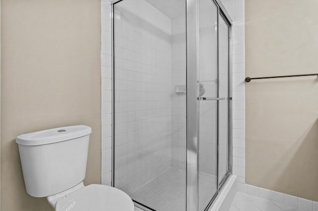 bathroom featuring a shower with shower door and toilet