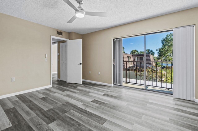 empty room with ceiling fan, light hardwood / wood-style flooring, and a textured ceiling