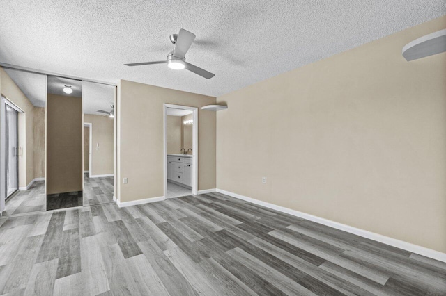 unfurnished bedroom with hardwood / wood-style floors, ceiling fan, a textured ceiling, and ensuite bathroom