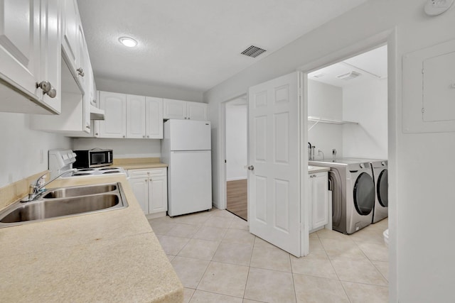 kitchen featuring separate washer and dryer, a sink, visible vents, freestanding refrigerator, and stainless steel microwave