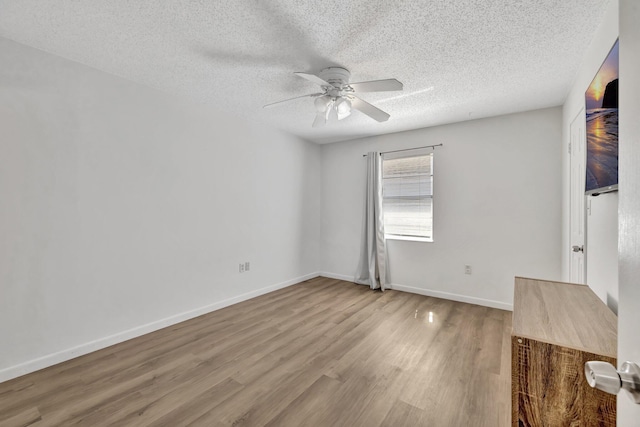 unfurnished bedroom with a ceiling fan, a textured ceiling, baseboards, and wood finished floors