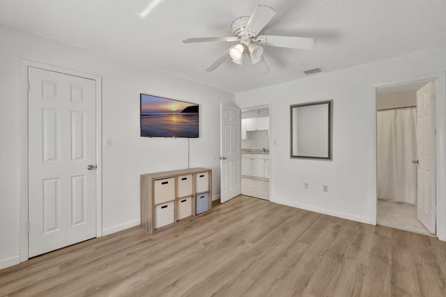 unfurnished bedroom with baseboards, light wood-style flooring, visible vents, and a textured ceiling