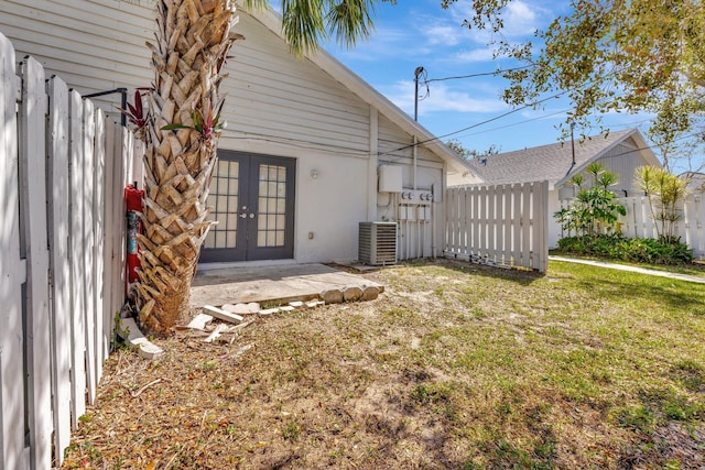 rear view of house with a yard, fence, cooling unit, and french doors