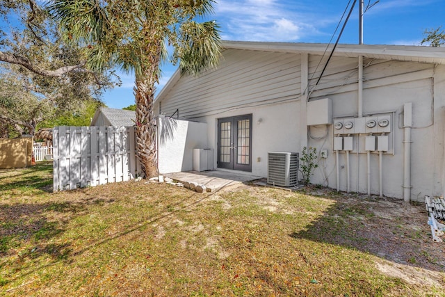 rear view of property with a yard, french doors, central AC unit, and fence