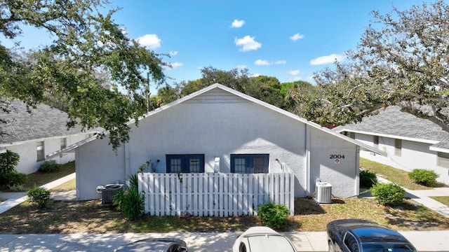 view of front of property with central AC unit, fence, and stucco siding