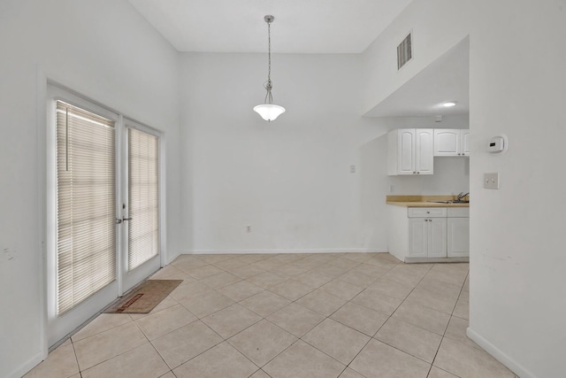 unfurnished dining area featuring light tile patterned floors, a sink, visible vents, and baseboards