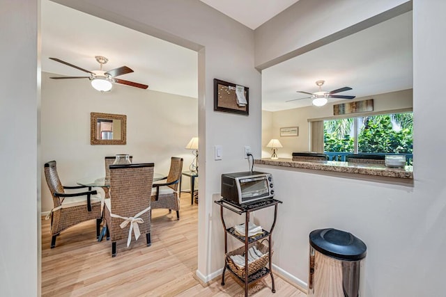 kitchen with light hardwood / wood-style flooring, light stone countertops, and ceiling fan