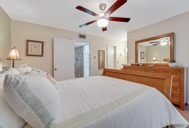 bedroom with wood-type flooring, ceiling fan, and ensuite bath