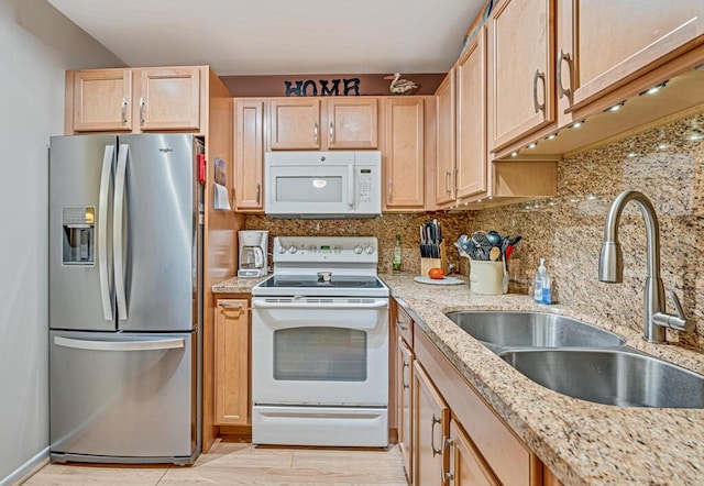 kitchen featuring light brown cabinetry, sink, white appliances, light stone countertops, and decorative backsplash