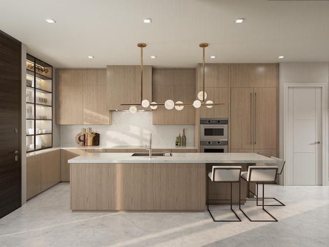 kitchen with sink, a kitchen island with sink, double oven, decorative light fixtures, and light brown cabinets