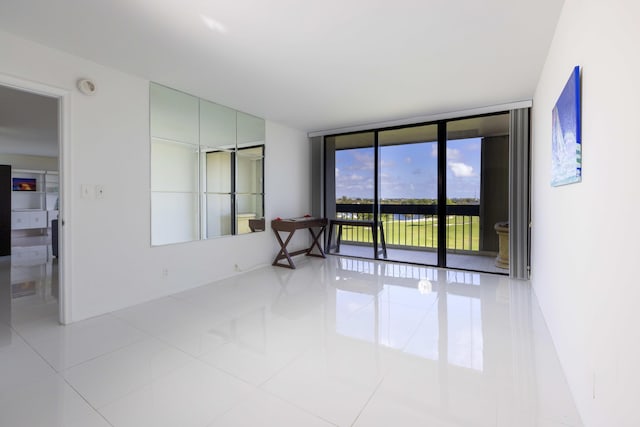 tiled empty room featuring floor to ceiling windows