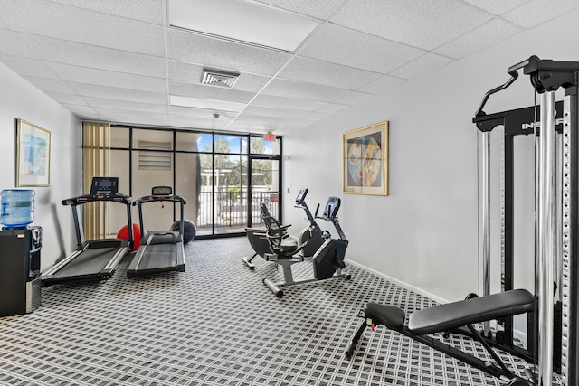 exercise room with expansive windows, carpet flooring, and a drop ceiling