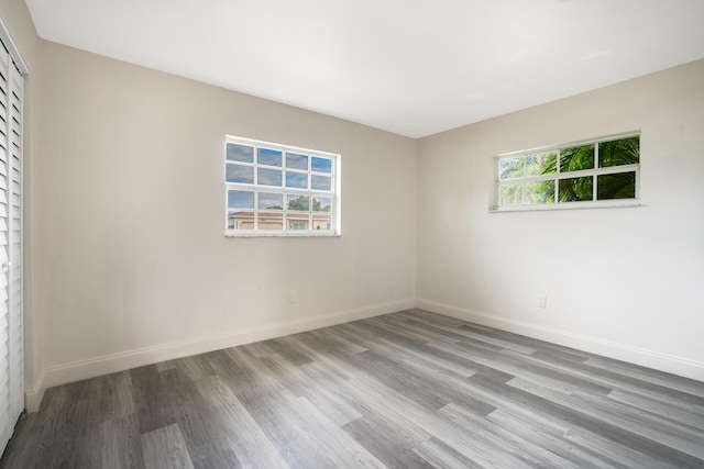 spare room featuring baseboards, a healthy amount of sunlight, and light wood finished floors