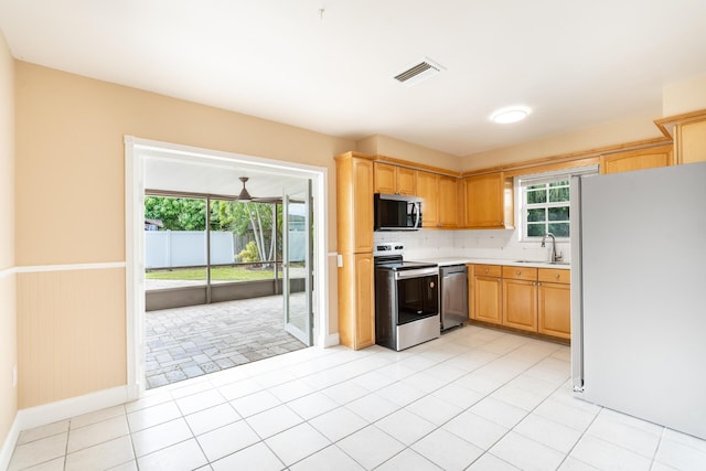 kitchen with stainless steel appliances, light countertops, visible vents, wainscoting, and a sink