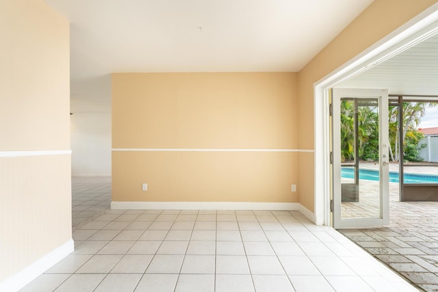spare room featuring a wainscoted wall, light tile patterned flooring, and baseboards