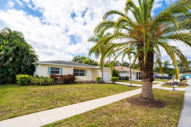 ranch-style home featuring a front lawn, concrete driveway, an attached garage, and stucco siding