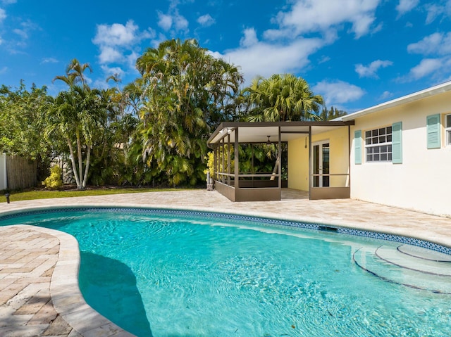 pool with a sunroom, fence, and a patio