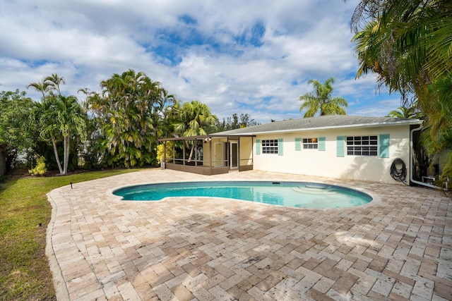outdoor pool with a sunroom and a patio