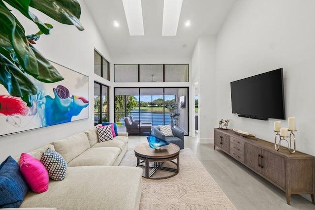 living room with a towering ceiling and a skylight