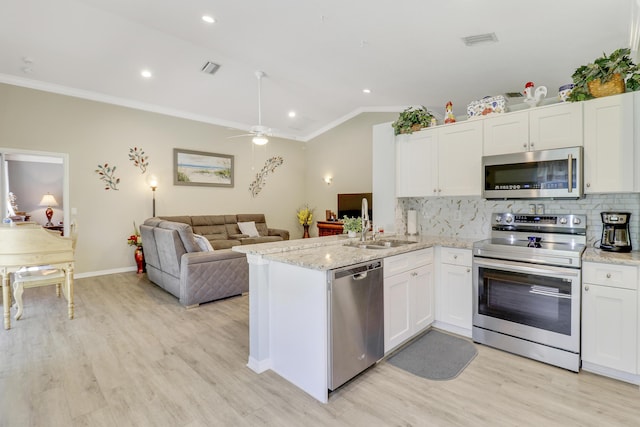 kitchen featuring lofted ceiling, kitchen peninsula, white cabinets, stainless steel appliances, and backsplash