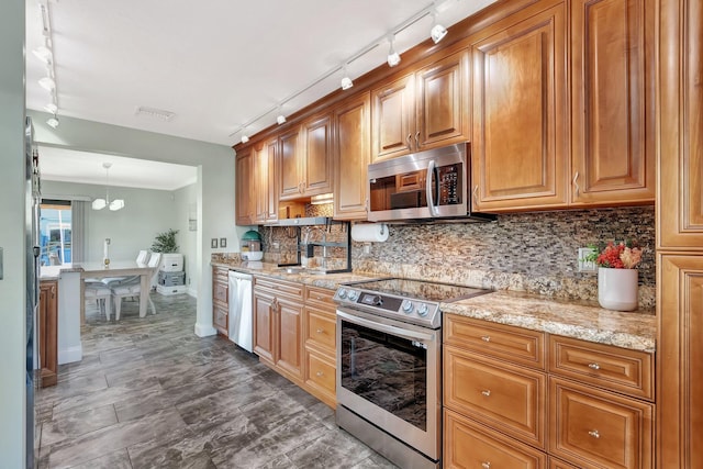 kitchen featuring tasteful backsplash, hanging light fixtures, stainless steel appliances, light stone countertops, and sink