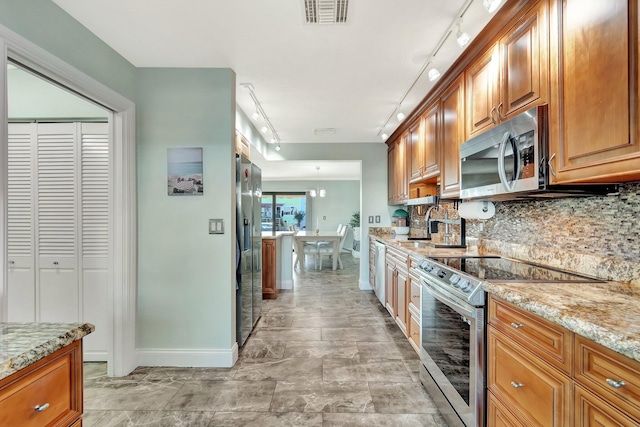 kitchen with light stone countertops, backsplash, stainless steel appliances, and sink