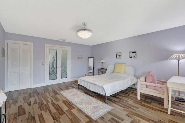 bedroom featuring french doors, light hardwood / wood-style floors, and a closet