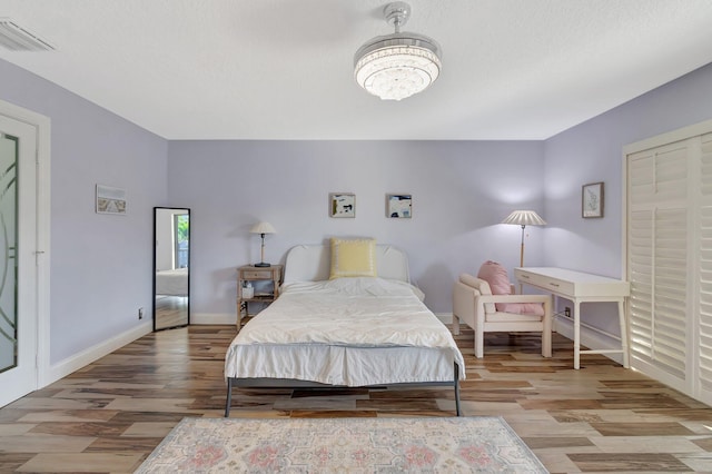 bedroom featuring a textured ceiling, hardwood / wood-style flooring, and a chandelier