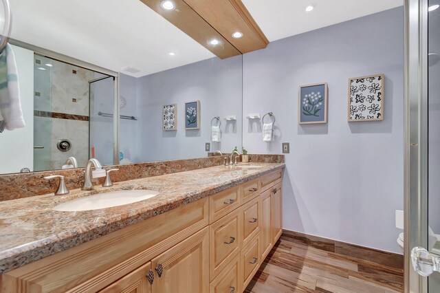 bathroom featuring toilet, vanity, an enclosed shower, and wood-type flooring