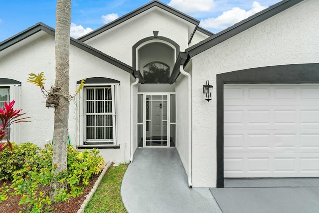 entrance to property featuring an attached garage and stucco siding