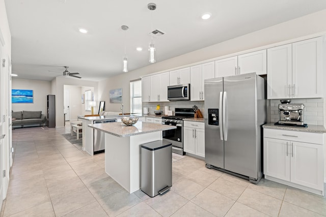 kitchen with white cabinetry, decorative light fixtures, stainless steel appliances, and a center island