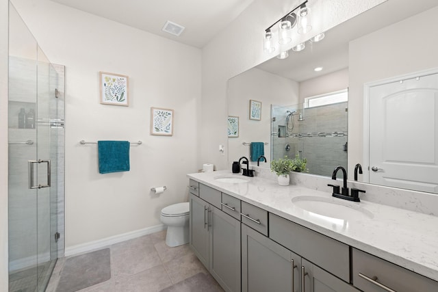 bathroom featuring tile patterned floors, vanity, toilet, and a shower with shower door