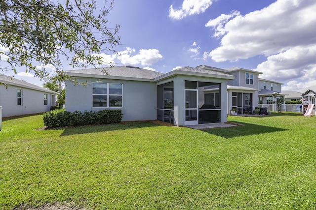 back of property featuring a sunroom and a lawn