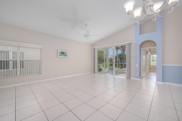 empty room with light tile patterned flooring, ceiling fan with notable chandelier, and high vaulted ceiling