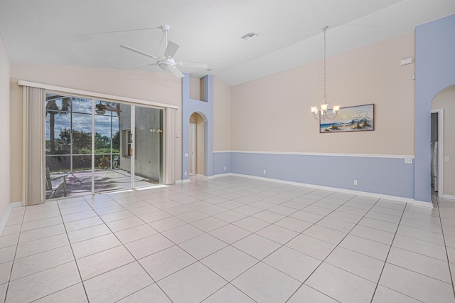 empty room with high vaulted ceiling, ceiling fan with notable chandelier, and light tile patterned floors