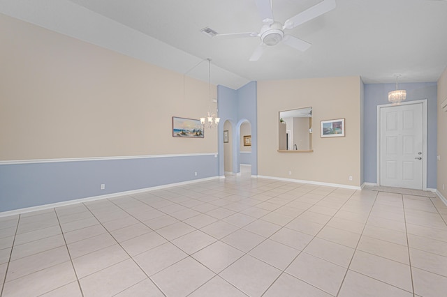 empty room with lofted ceiling, ceiling fan with notable chandelier, and light tile patterned flooring