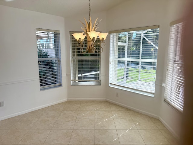 tiled spare room featuring an inviting chandelier