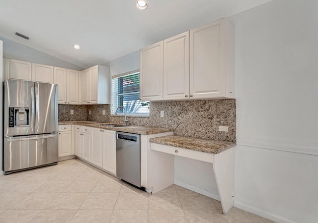 kitchen featuring light stone counters, appliances with stainless steel finishes, a sink, backsplash, and light tile patterned flooring