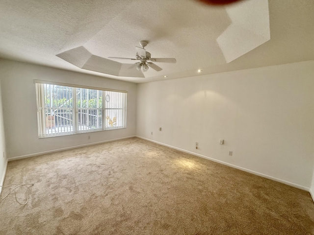 unfurnished room featuring ceiling fan, a tray ceiling, carpet, and a textured ceiling