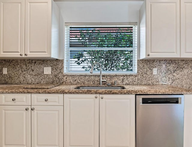 kitchen with tasteful backsplash, stainless steel dishwasher, a sink, and white cabinets