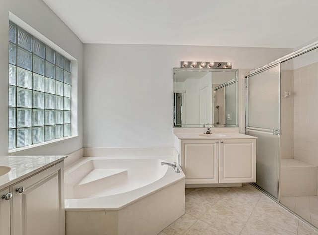 bathroom featuring tile patterned floors, a sink, a garden tub, a shower stall, and two vanities