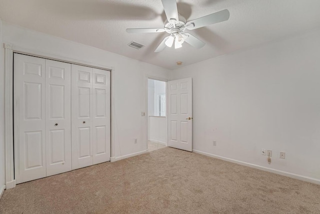 unfurnished bedroom with baseboards, visible vents, a ceiling fan, carpet, and a closet