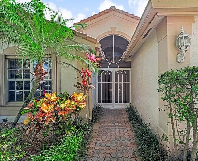 property entrance with a tile roof and stucco siding