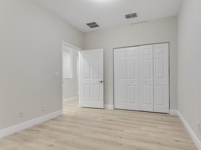 unfurnished bedroom with light hardwood / wood-style flooring and a closet