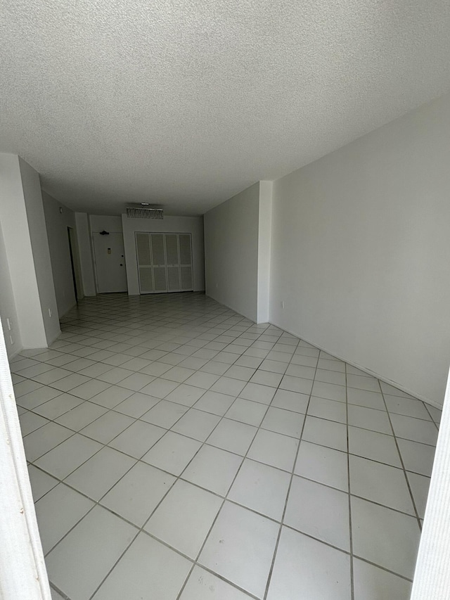 tiled empty room with a textured ceiling