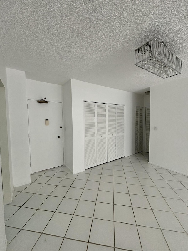 interior space with light tile patterned floors, a closet, and a textured ceiling